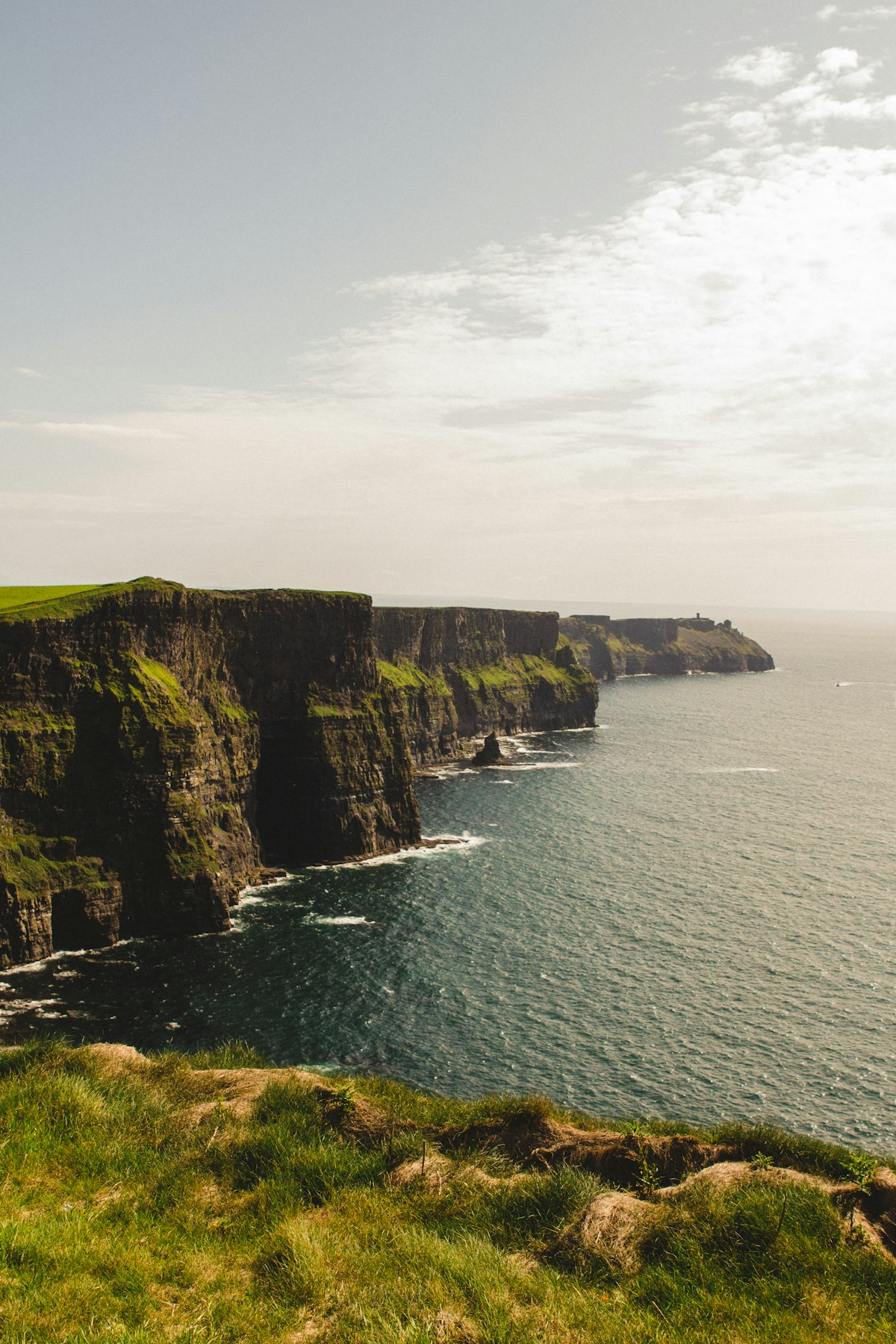 Dramatic coastal cliffs meeting a stormy ocean under dark clouds